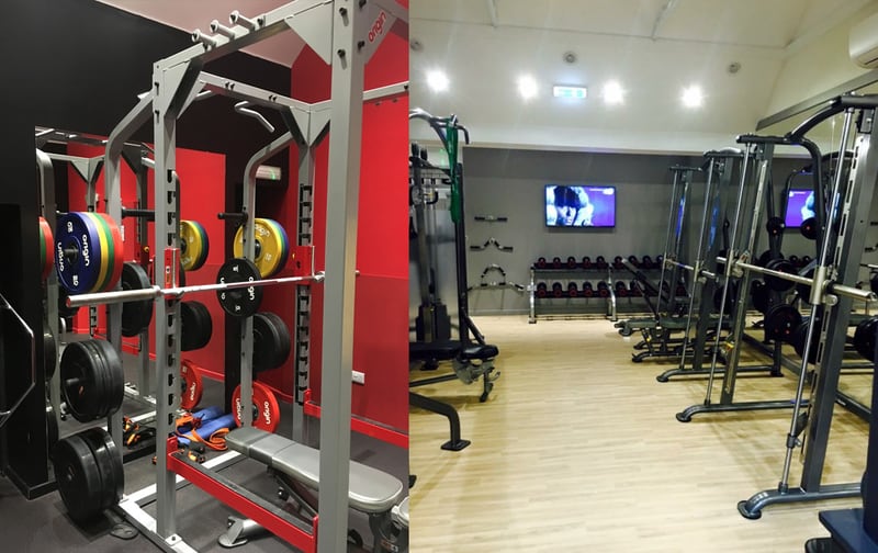 Power racks with red Olympic plates, and the weights floor beyond